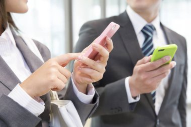 İş kadını ve işadamı ofiste akıllı telefon kullanıyor. 