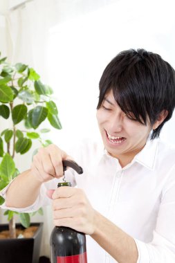 Genç yakışıklı adam mutfakta şarap açıyor.