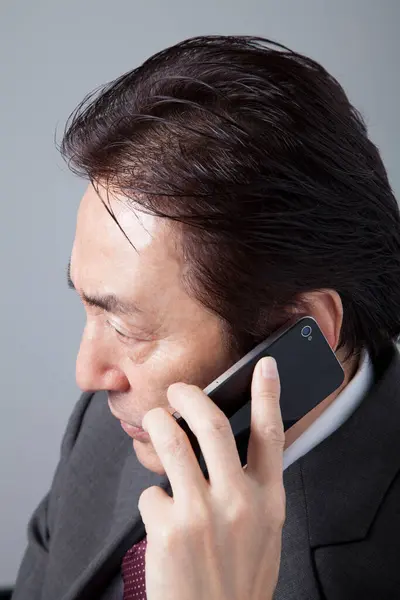 グレイを背景にした日本人ビジネスマン スマートフォンを使用して灰色のスーツのアジア人男性の肖像画 — ストック写真
