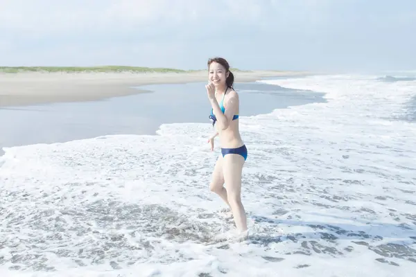 身穿蓝色比基尼的年轻亚洲女人在夏季海滩度假 — 图库照片