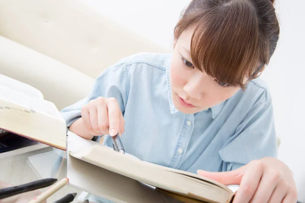 本とペンで自宅で勉強している若い日本人女性 — ストック写真