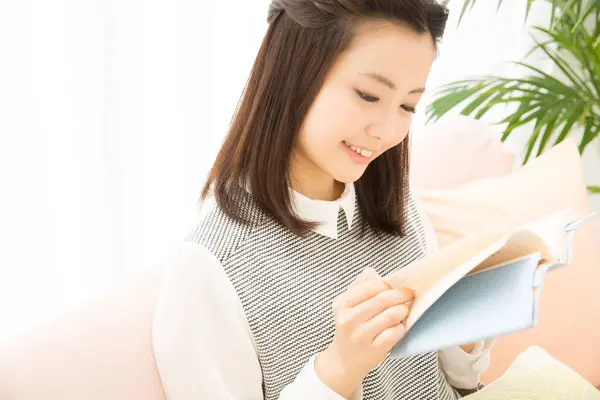 自宅で本を読んでいる若い日本人女性の笑顔 — ストック写真