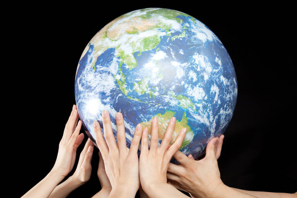 the human hands holding a globe on black background