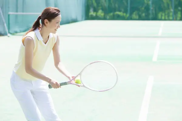 Sarayda tenis oynayan genç Asyalı kadın.