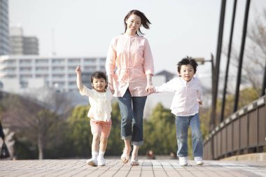 Asyalı anne, kızı ve oğlu köprüde yürüyor. 
