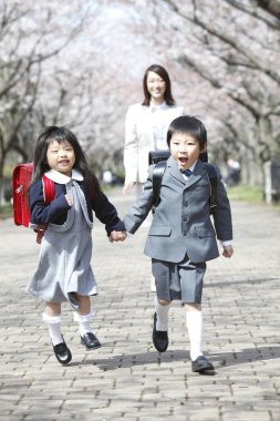 Parkta çocuklu Asyalı anne ve çiçek açan ağaçlar.