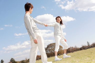 Mavi gökyüzünün altında el ele tutuşan çift