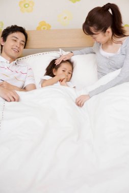 Asyalı bir aile yatakta yatıyor.