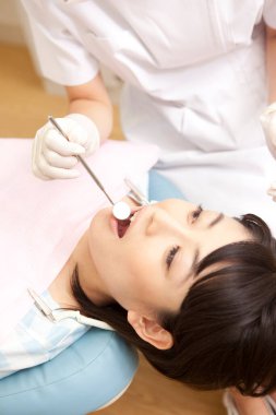 Kadın diş hekimi klinikteki kadın hastayı muayene ediyor. 