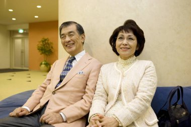 Kanepede oturan yaşlı Asyalı çift.