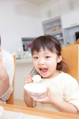 Asyalı anne ve kız kahvaltı yapıyorlar.