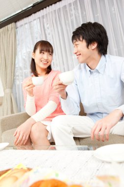 Gülümseyen çift kanepede kahve içiyor.