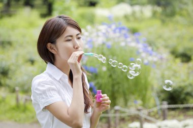 Kadın sabun köpüğü üflüyor.