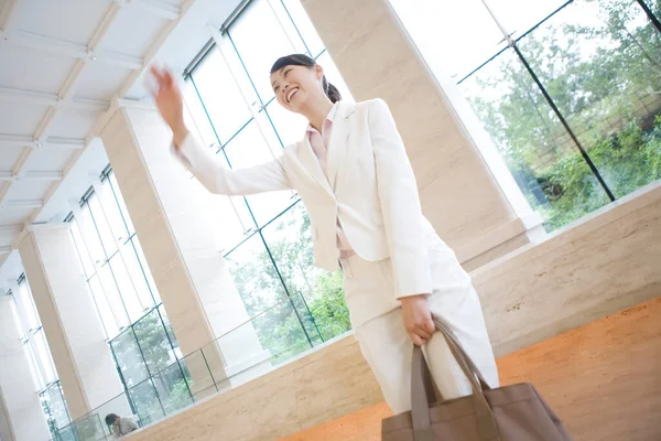 young Asain businesswoman waving to somebody in the office