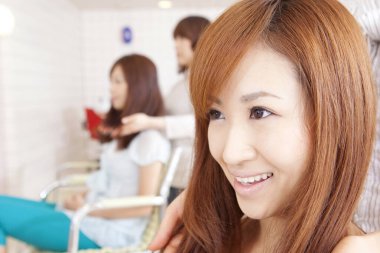 Güzellik salonundaki genç Asyalı kadın saçını kestirecek.  