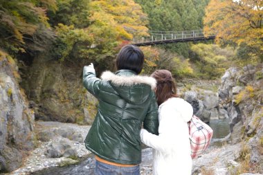 Sonbahar ormanlarında mutlu Asyalı turistler, seyahat konsepti.