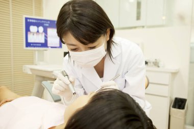 Kadın diş hekimi klinikteki kadın hastayı muayene ediyor. 