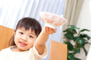 Gülümseyen kız parlak odada kaseyi tutuyor.