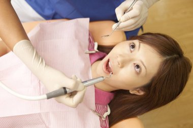 Dişçi hastanın dişlerini muayene ediyor. 