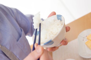 Mutfakta pirinç yiyen bir kadının yakın plan fotoğrafı.