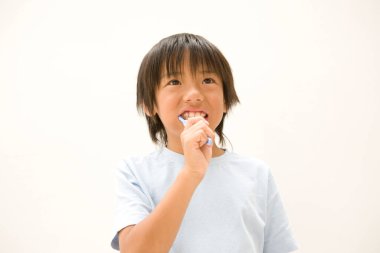 Küçük Asyalı çocuk banyoda dişlerini fırçalıyor.