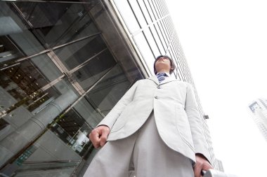 Genç Asyalı adam şehirde duruyor. 