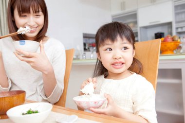 Asyalı anne ve kız kahvaltı yapıyorlar.