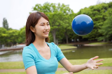 Parkta top oynayan Asyalı genç kadın. 