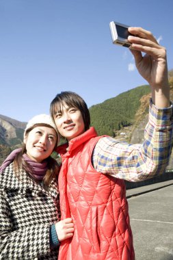 Genç çift fotoğraf makinesiyle selfie çekiyor. 