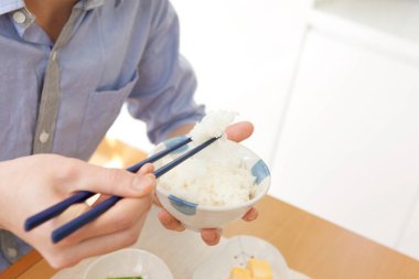 Genç Asyalı adam yeme pirinç çubuk ile