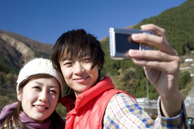 Asyalı çift fotoğraf makinesiyle selfie çekiyor. 