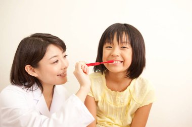 Doktor ve küçük kızı dişlerini fırçalıyorlar.