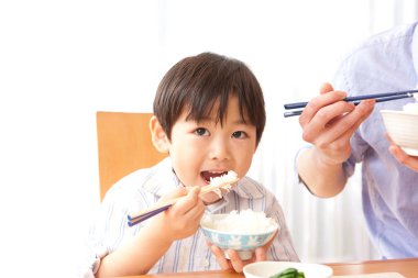 Küçük çocuk çubukla pilav yiyor.