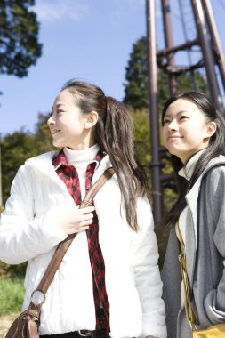 Kablolu yayının altında duran iki Asyalı kadın