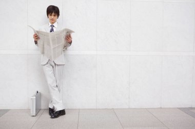 Ofis duvarının önünde gazetesi olan bir işadamı.