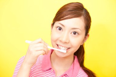 Genç Japon kadın diş fırçasıyla dişlerini fırçalıyor.