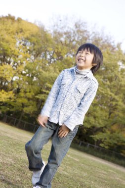 gülümseyen Asyalı çocuk parkta oynuyor.