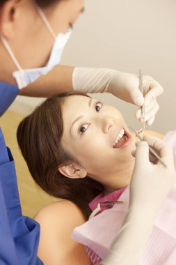 Dişçi hastanın dişlerini muayene ediyor. 