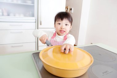 Sarı tencereyle yemek yapan genç kız.