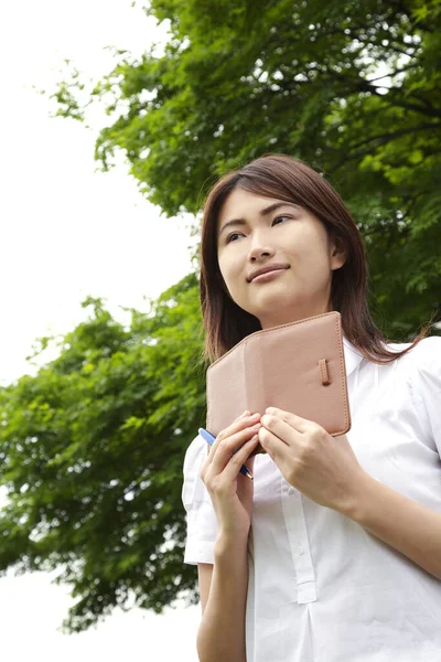 portrait of asian woman student with notebook in park