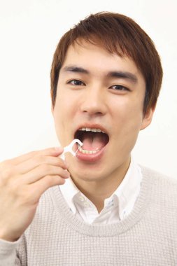 Dişleri temizlemek için diş ipi kullanan Japon 'un stüdyo portresi.
