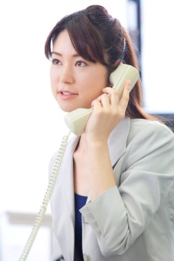 Masada otururken telefonla konuşan bir kadın. 