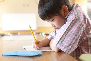 Sıkıcı Japon okul çocuğu sınıfta çalışıyor.