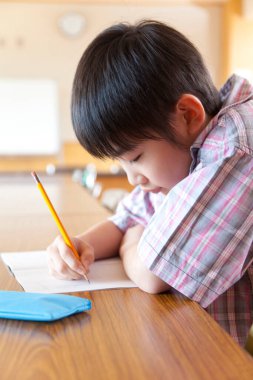 Sıkıcı Japon okul çocuğu sınıfta çalışıyor.