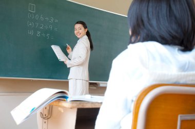 Asyalı liseli kız sınıfta öğretmenle çalışıyor.