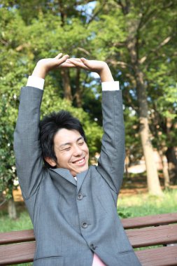 Takım elbiseli bir adam bankta oturmuş dinleniyor.