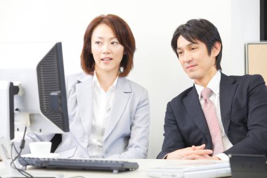 Bir adam ve bir kadın bilgisayar başında oturuyor.