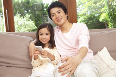 Asyalı küçük baba ve uzaktan kumandalı küçük kız. 