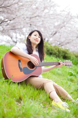 Parkta gitarlı genç Asina kadın. 