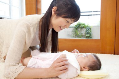 Genç Asyalı anne ve bebeği oturma odasında.